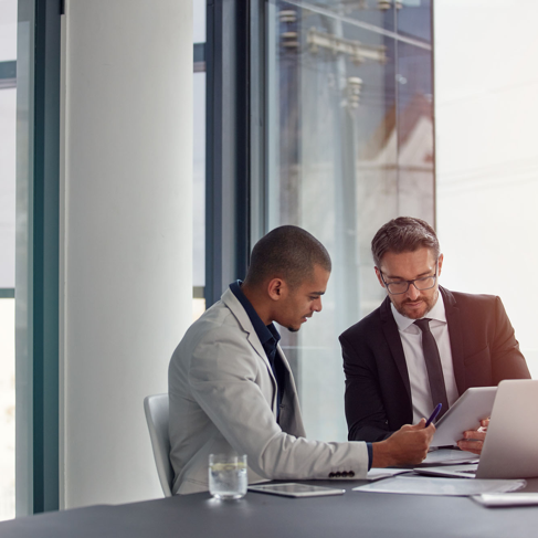 Two businessmen looking at a tablet in a modern office