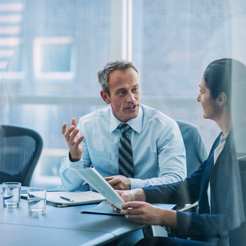 Businessman discussing strategy with female colleague at conference table in office